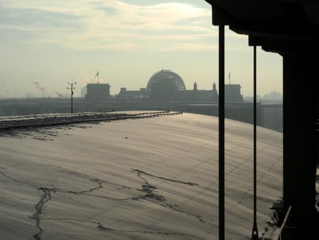 Industriekletterer von ZITRAS bei der Schneebeseitigung und Eiszapfenentfernung auf einem Dach mit Blick auf verschneite Stadtlandschaft