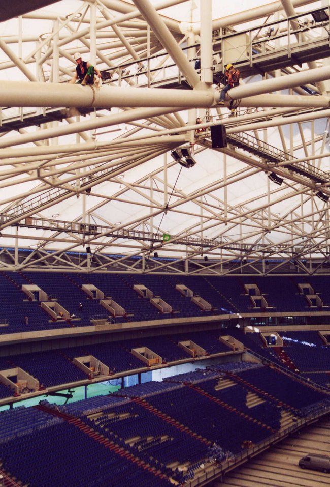 Industriekletterer bei Reinigungsarbeiten auf dem Dach eines Stadions mit blauen Sitzen