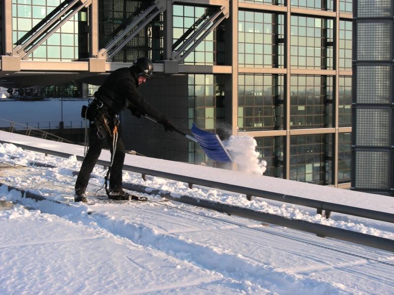 Ein Industriekletterer von ZITRAS bei der Schneebeseitigung auf Skiern