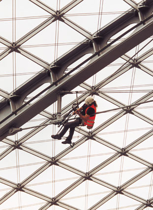 Eine Person an einer Seilrutsche, wahrscheinlich ein Industriekletterer von ZITRAS in Sicherheitsweste während einer Schulung oder Demonstration einer Höhenarbeitstechnik.