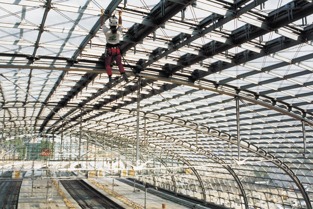 Eine Person während einer Schulungssituation auf einem Dach, die Höhenarbeitsausrüstung wie Seile und Karabiner benutzt.