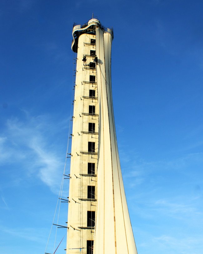 Ein hoher Aussichtsturm mit einem gewundenen Design, bei blauem Himmel.