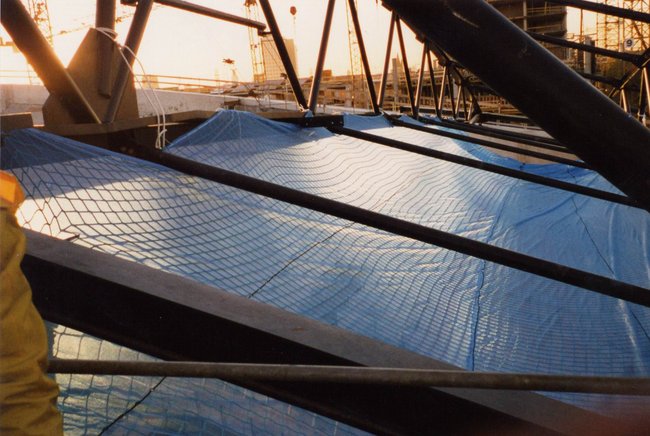 Struktur in einem Bauprojekt mit Metallträgern und blauer Schutzplane.