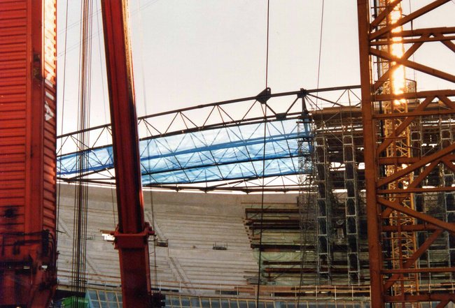 Konstruktion eines Stadiondachs mit blauer Abdeckung bei einer Baustelle.