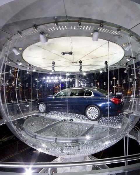 Ein Auto in einer gläsernen, kugelförmigen Struktur, die wie eine Sanduhr aussieht.